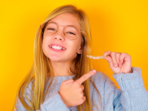 criança sorrindo e segurando aparelho invisível na mão