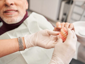 homem e dentista segurando prótese